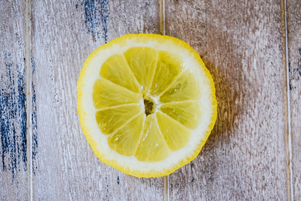 a close up of a lemon slice on a pale white washed wooden plank