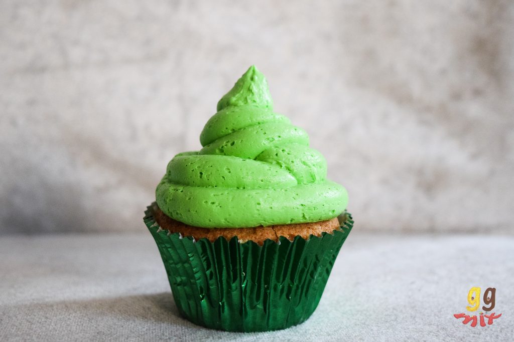 a cupecake in a metalic green cupcake case with lime green buttercream on the top
