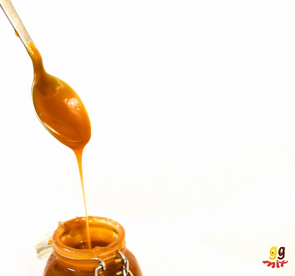 a spoon of salted caramel being taken out of a jar