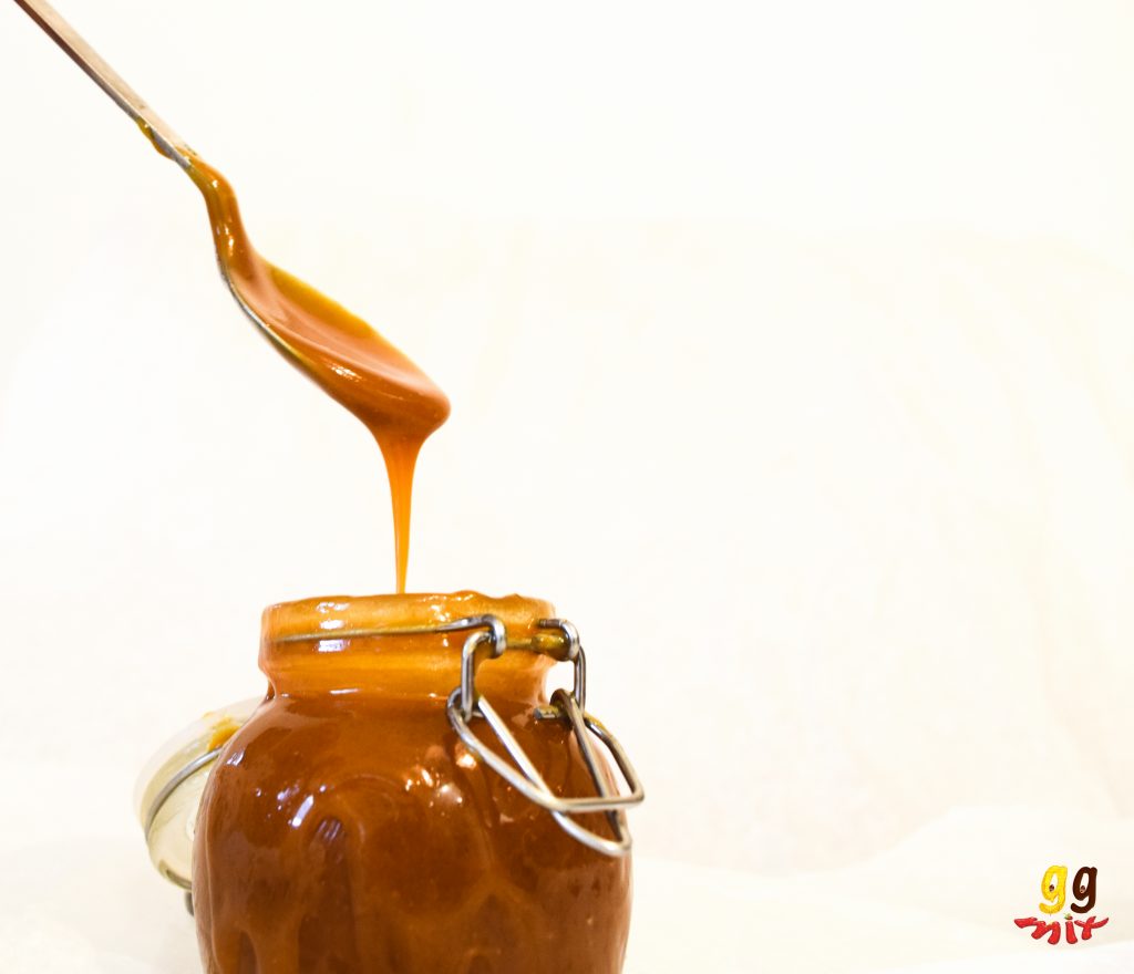 a spoon of salted caramel being taken out of a jar