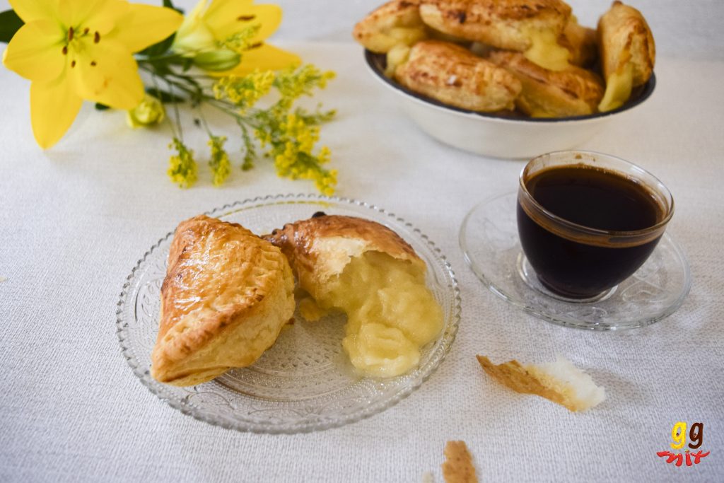 A bowl and plate full of Bougatsa puff pastry hand pie filled with Greek semolina custard and a cup of Greek coffee