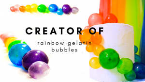 two rows of rainbow coloured gelatin balls and a white tall cake with rainbow gelatin baubbles swirling down the side