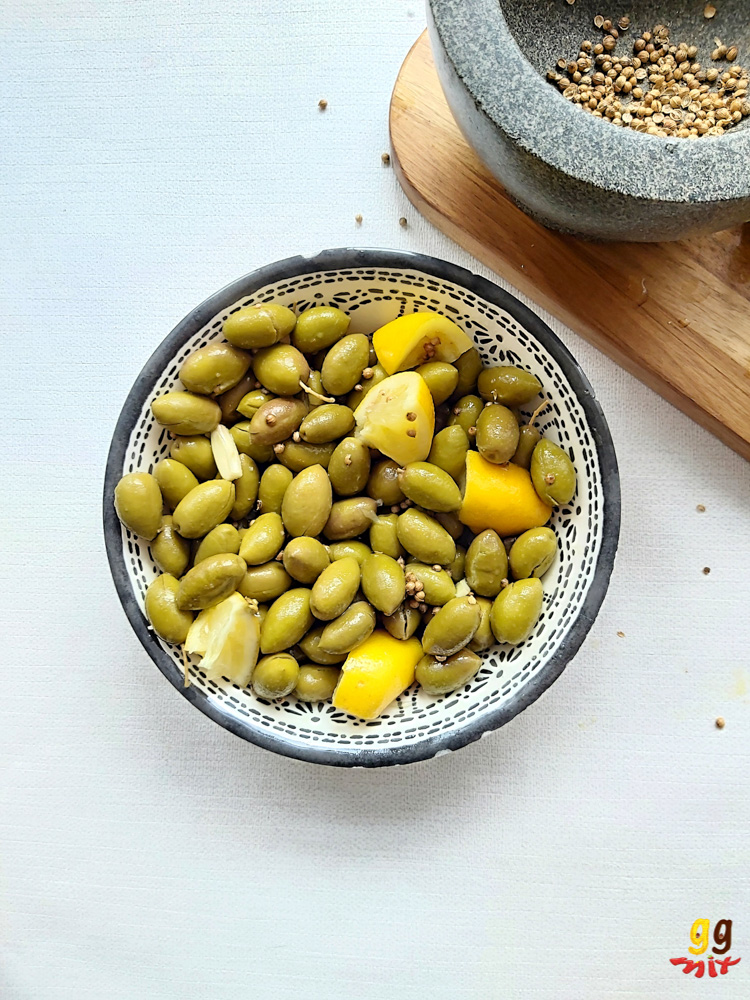ELIES TSAKISTES GREEK CRACKED GREEN OLIVES IN A BOWL WITH PESTAL AND MORTAR