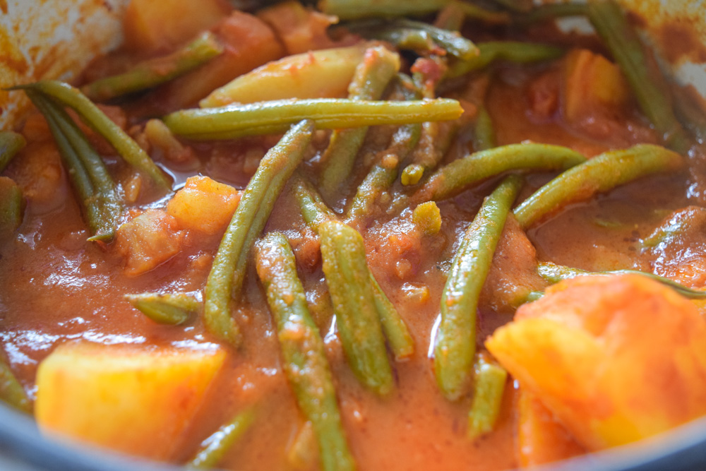a pot of fasolakia green beans and potatoes in a tomatoe sauce